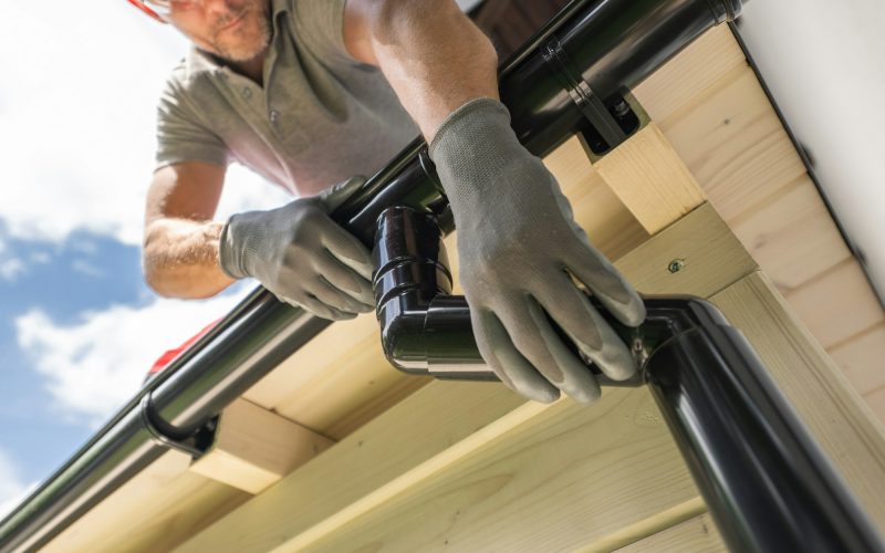 Worker Installing Gutter System on Roof